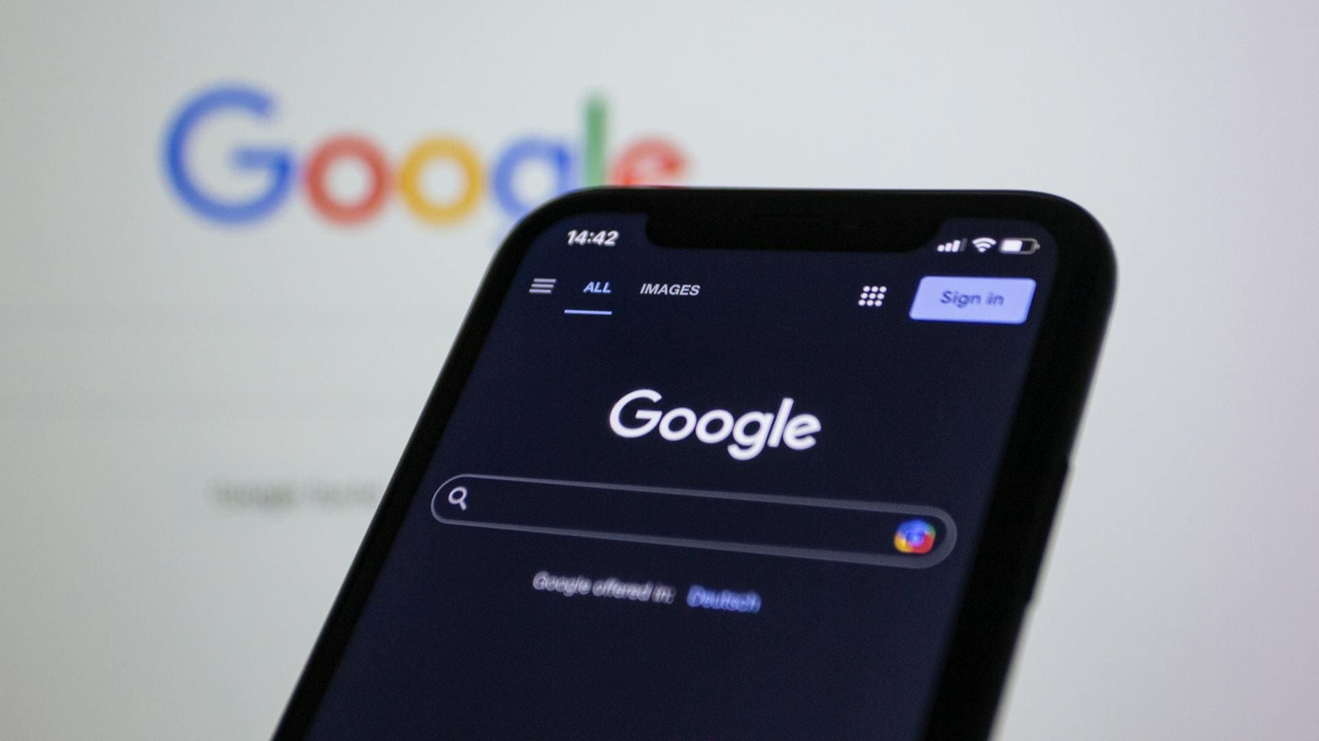 E-Commerce Developer; The image shows a close-up of a cell phone with the Google search bar displayed on the screen. The time is 2:42 pm and the language is set to Dutch.  There are four options displayed below the search bar: All, Images, Sign in, and Google.